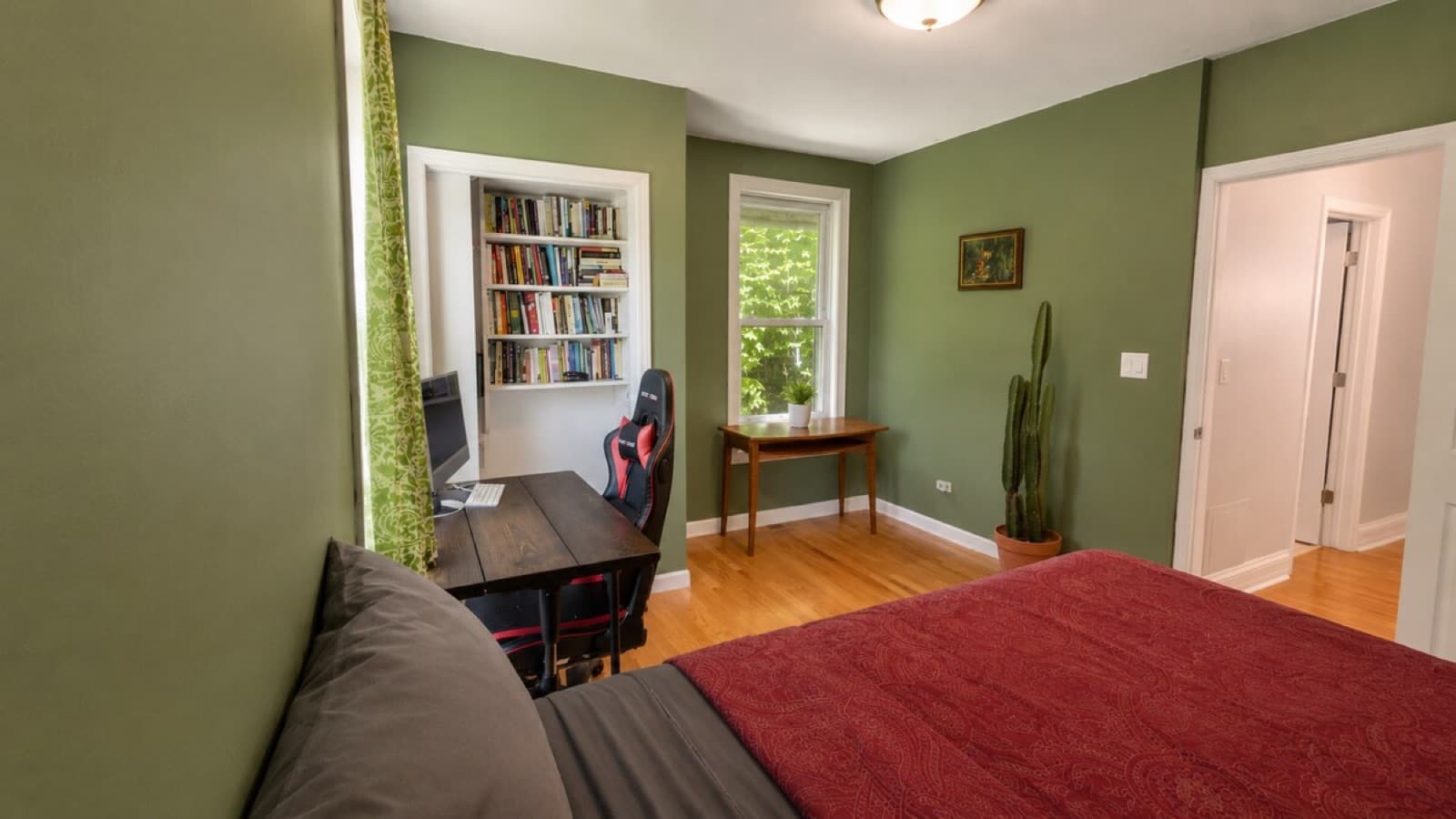 Third bedroom with painted walls, built-in shelves, and hardwood floors